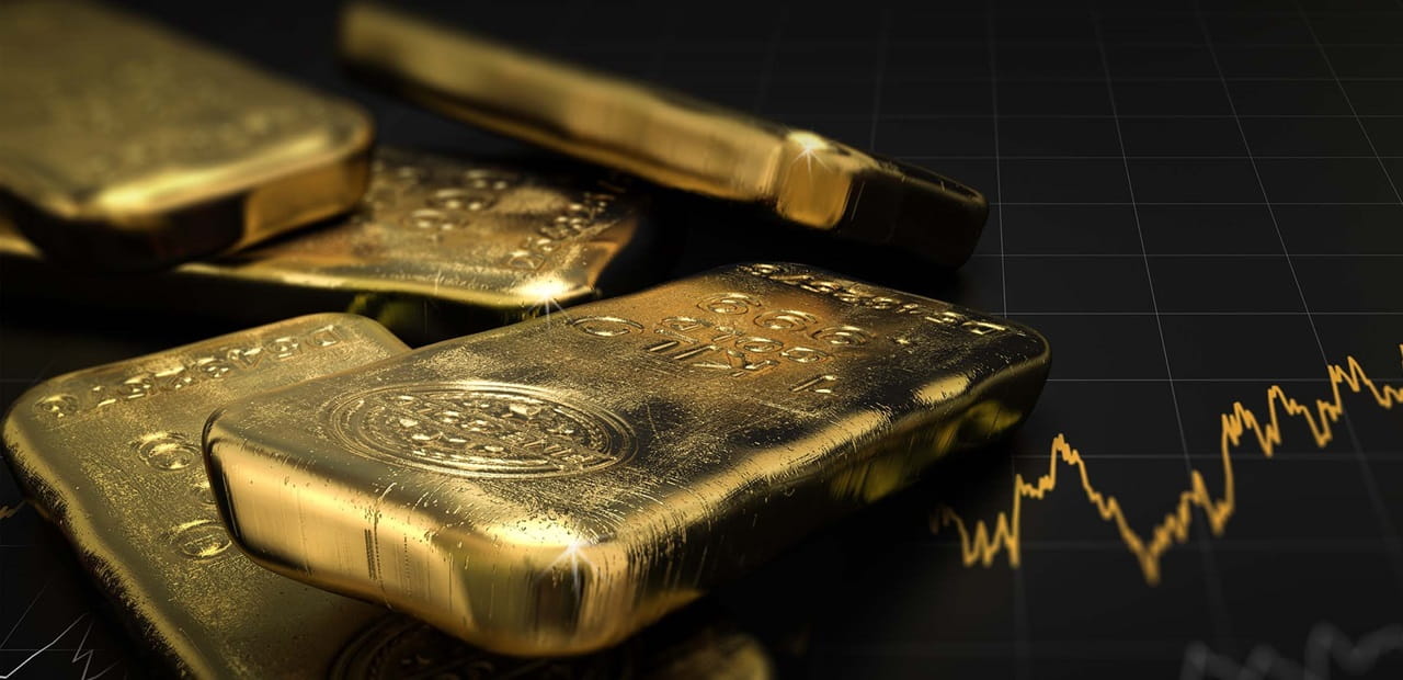 A stack of gold bars sits next to a gold-colored image of a stock market graph
