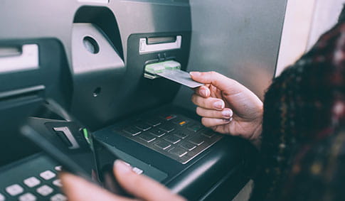Hand of young woman inserting credit card into cash machine