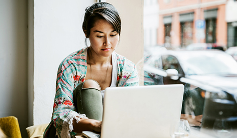 Young Woman Working On Laptop In Cafe Window