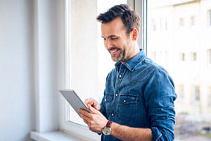 Smiling man using tablet at the window